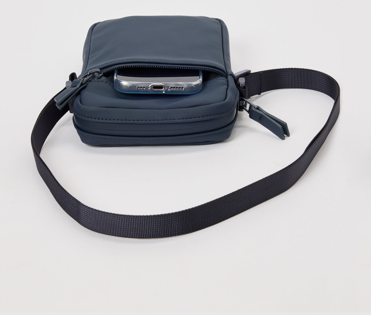 Niebieska przeciwdeszczowa torebka na ramię z telefonem w kieszeni.