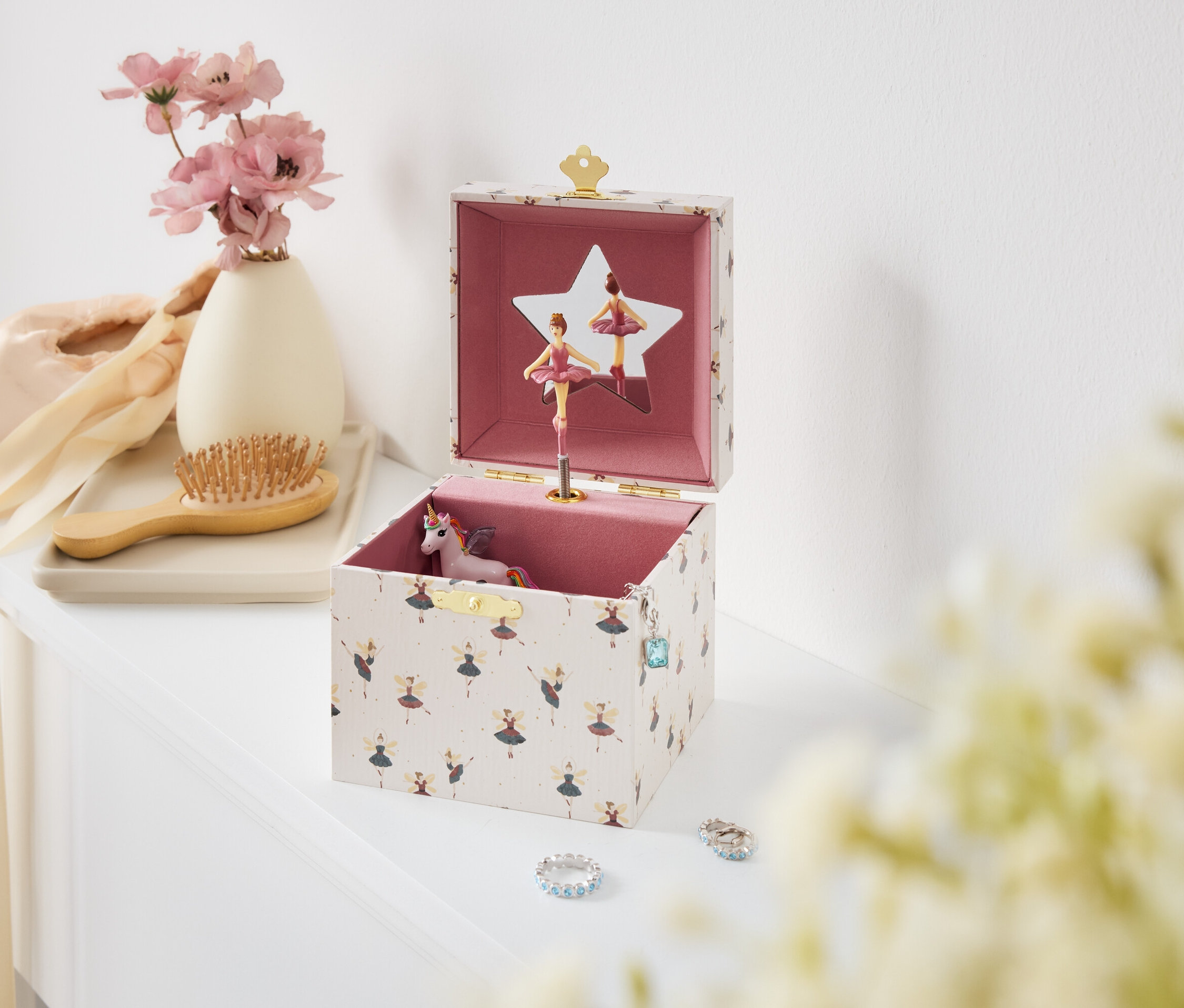 Otwarta pozytywka z baletnicami i jednorożcem na białym stole.