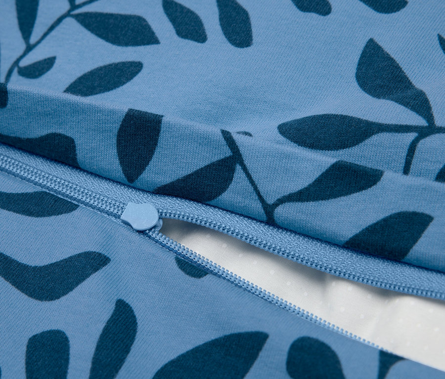 Zbliżenie niebieskiej pościeli z zamkiem błyskawicznym i wzorem liści.
