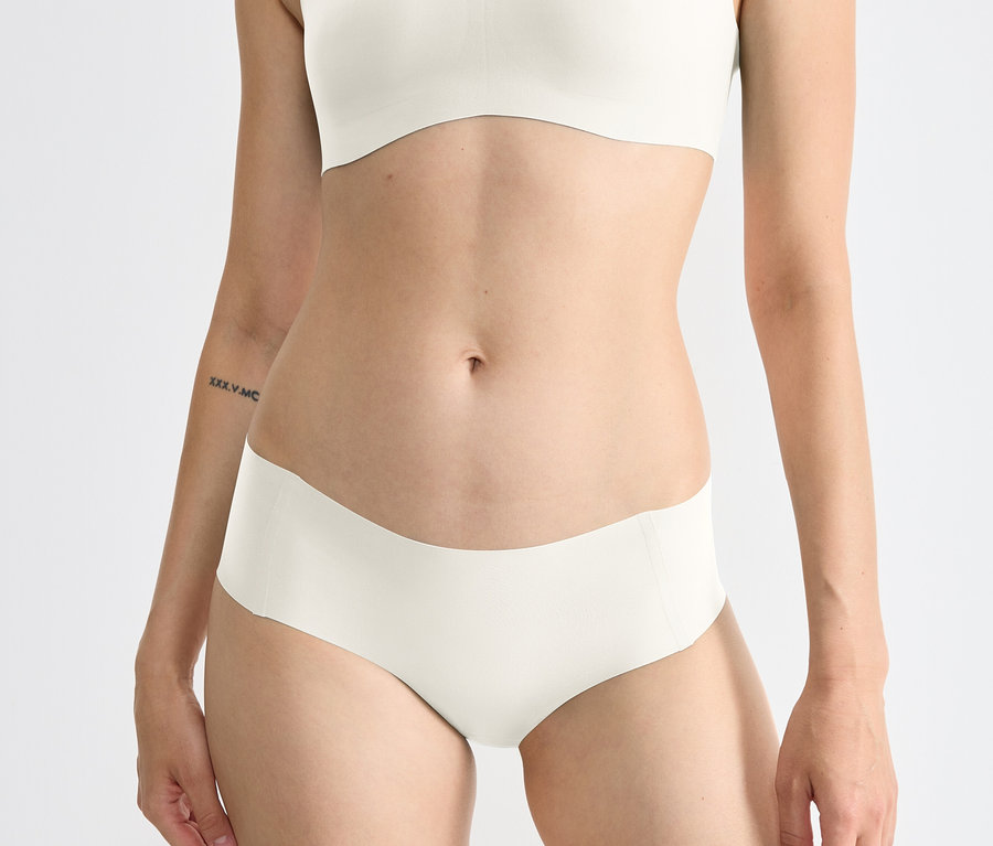 Na zdjęciu zbliżenie na tors kobiety ubranej w hipstery sloggi ZERO Feel 2.0, jedwabista biel.