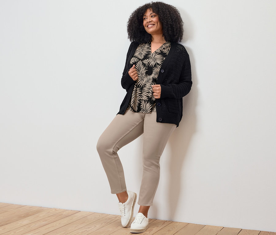 Kobieta pozuje w tregginsach o długości 7/8, topie i kardiganie.