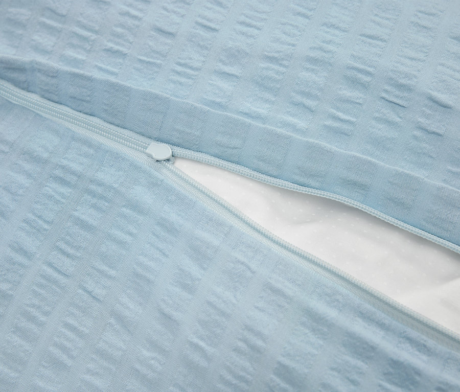 Zbliżenie na jasno-niebieską poszewkę na poduszkę z zamkiem błyskawicznym i białą wewnętrzną warstwą.