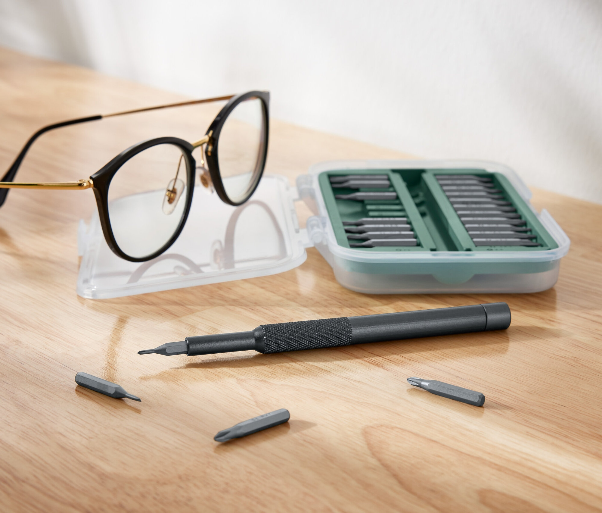 Okulary leżą obok otwartego zestawu wkrętaków precyzyjnych.