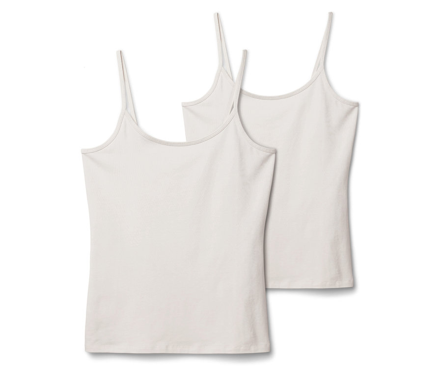 Dwie białe koszulki na ramiączkach leżą obok siebie na białym tle.