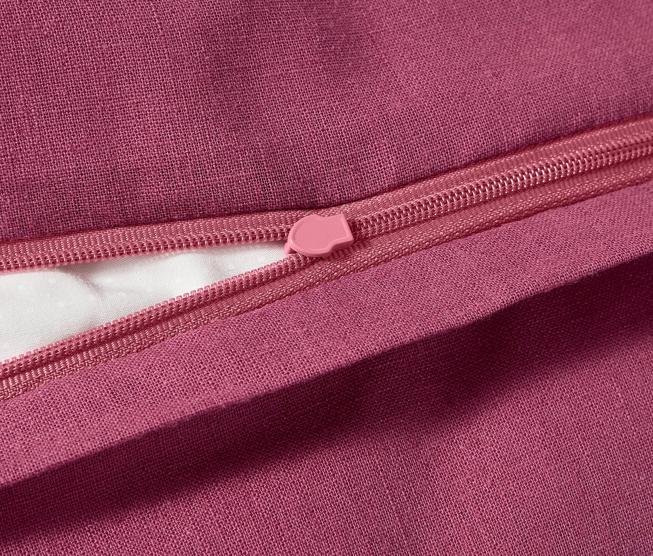 Zbliżenie na pościel z lnu i bawełny w niestandardowym rozmiarze z różowym zamkiem błyskawicznym.