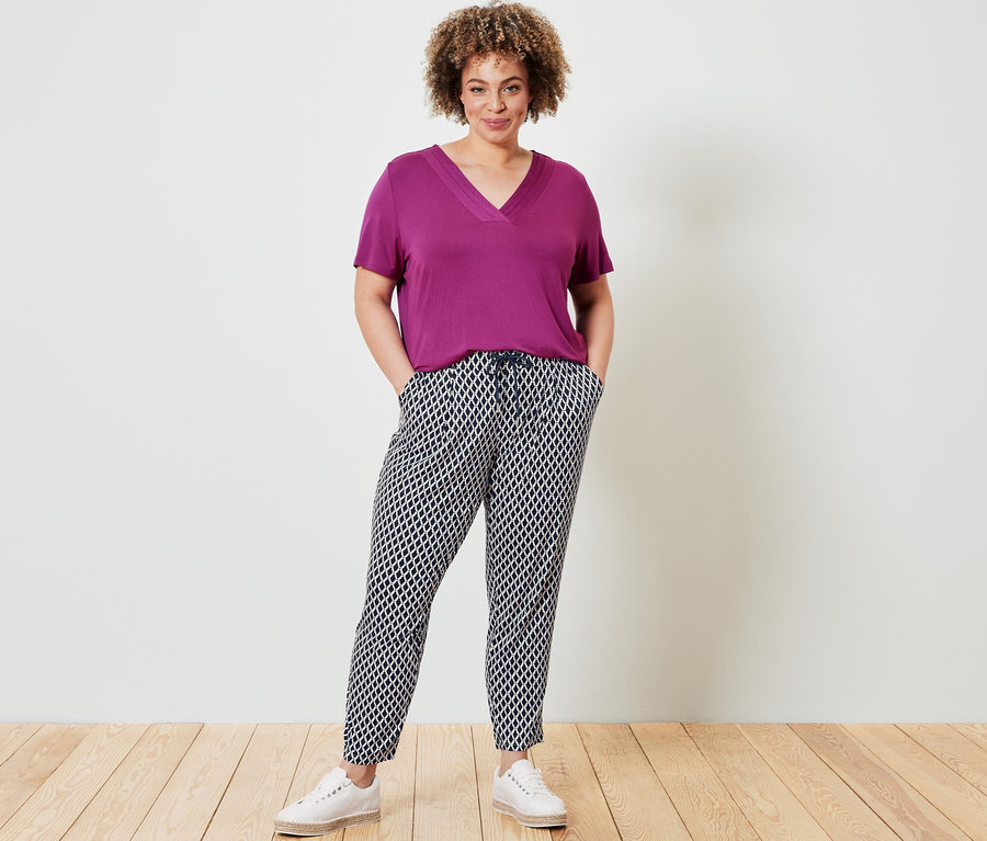 Kobieta pozuje w Koszulce, jagodowa i Wzorzystych spodniach z dżerseju.