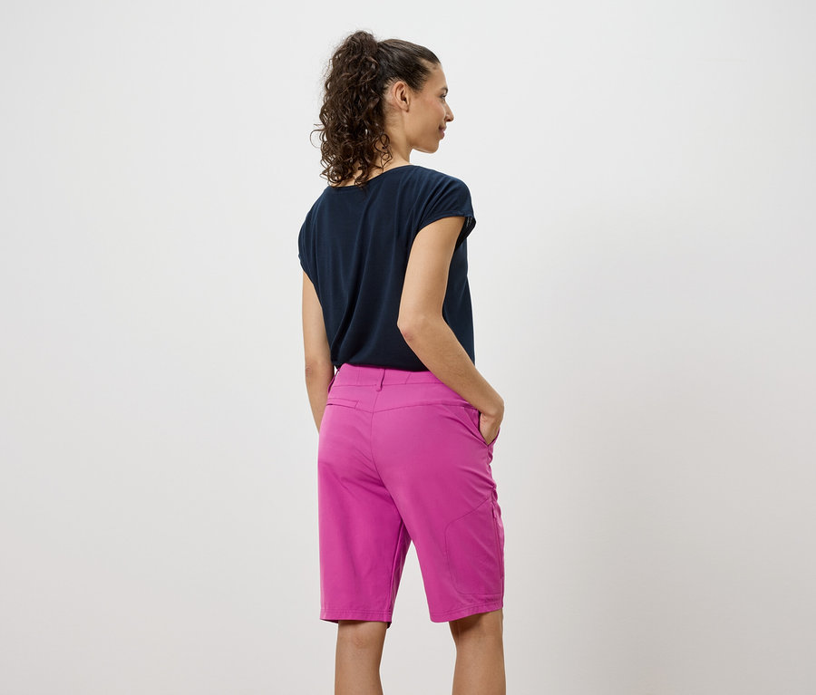 Widok z tyłu kobiety w ciemnej koszulce i różowych szortach.