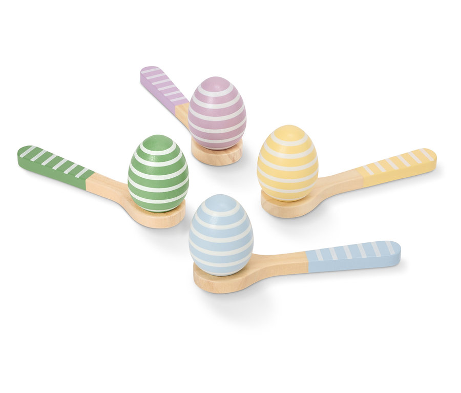 Cztery malowane, paskowane pisanki w pastelowych kolorach leżą na małych drewnianych łyżkach.