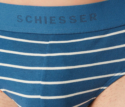 Mężczyzna nosi niebiesko-białe slipy SCHIESSER Rio w paski. Niebieski pas ma logo SCHIESSER.