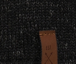 Zbliżenie na rękawiczkę z dzianiny polarowej z brązową etykietą z napisem EST 1949.