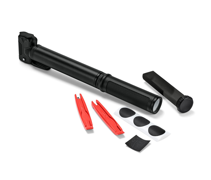 Czarna mała pompka rowerowa leży obok dwóch czerwonych łyżek do opon, łatek i papieru ściernego.