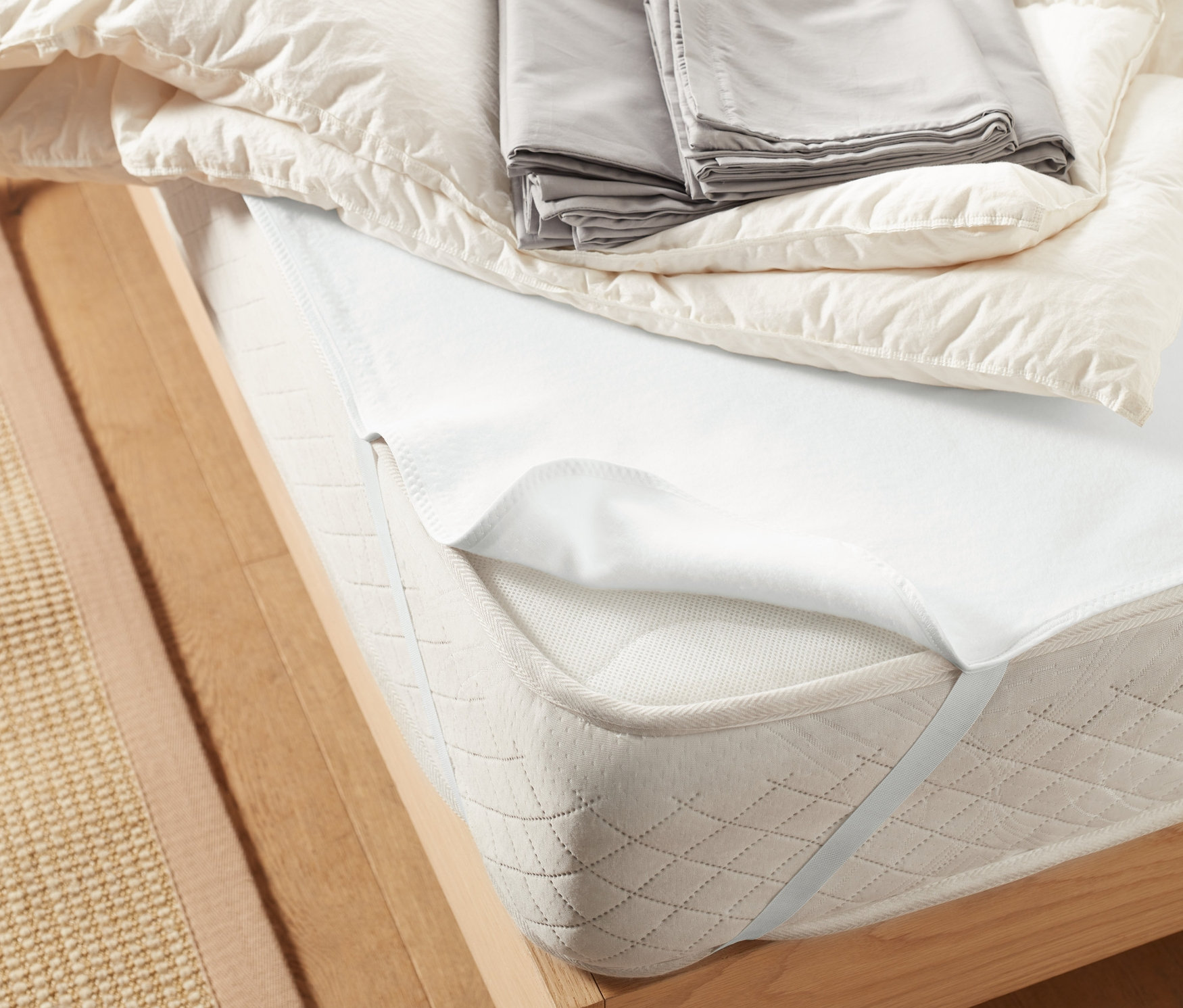 Łóżko z ochraniaczem na materac, ok. 140 x 200 cm, kołdrą i szarą pościelą.