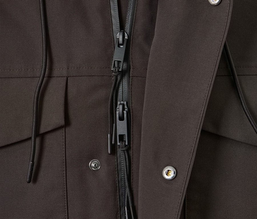 Zbliżenie na brązową parkę z czarnym zamkiem i srebrnymi zatrzaskami.