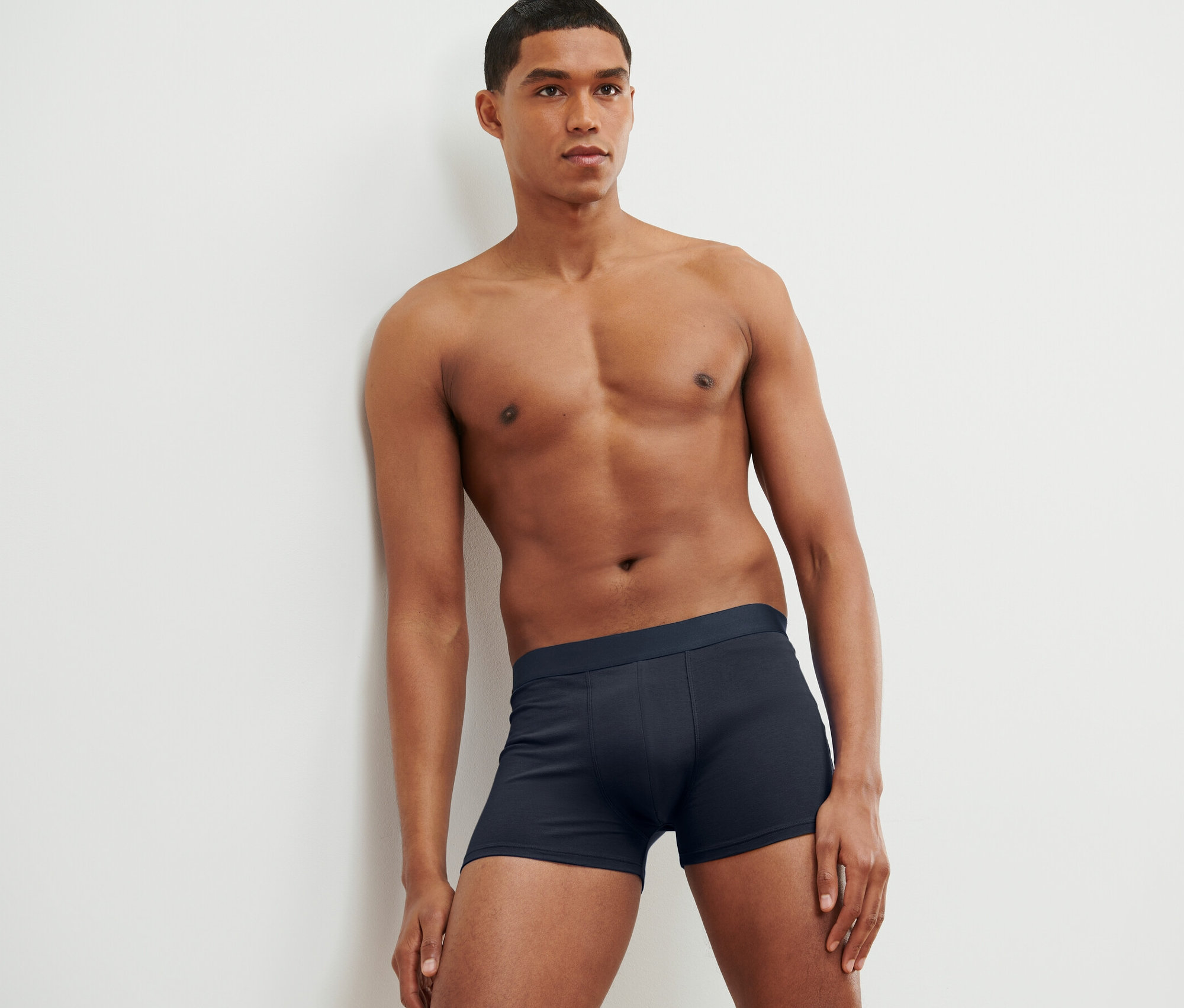 Mężczyzna oparty o ścianę ma na sobie bokserki, 4 pary.