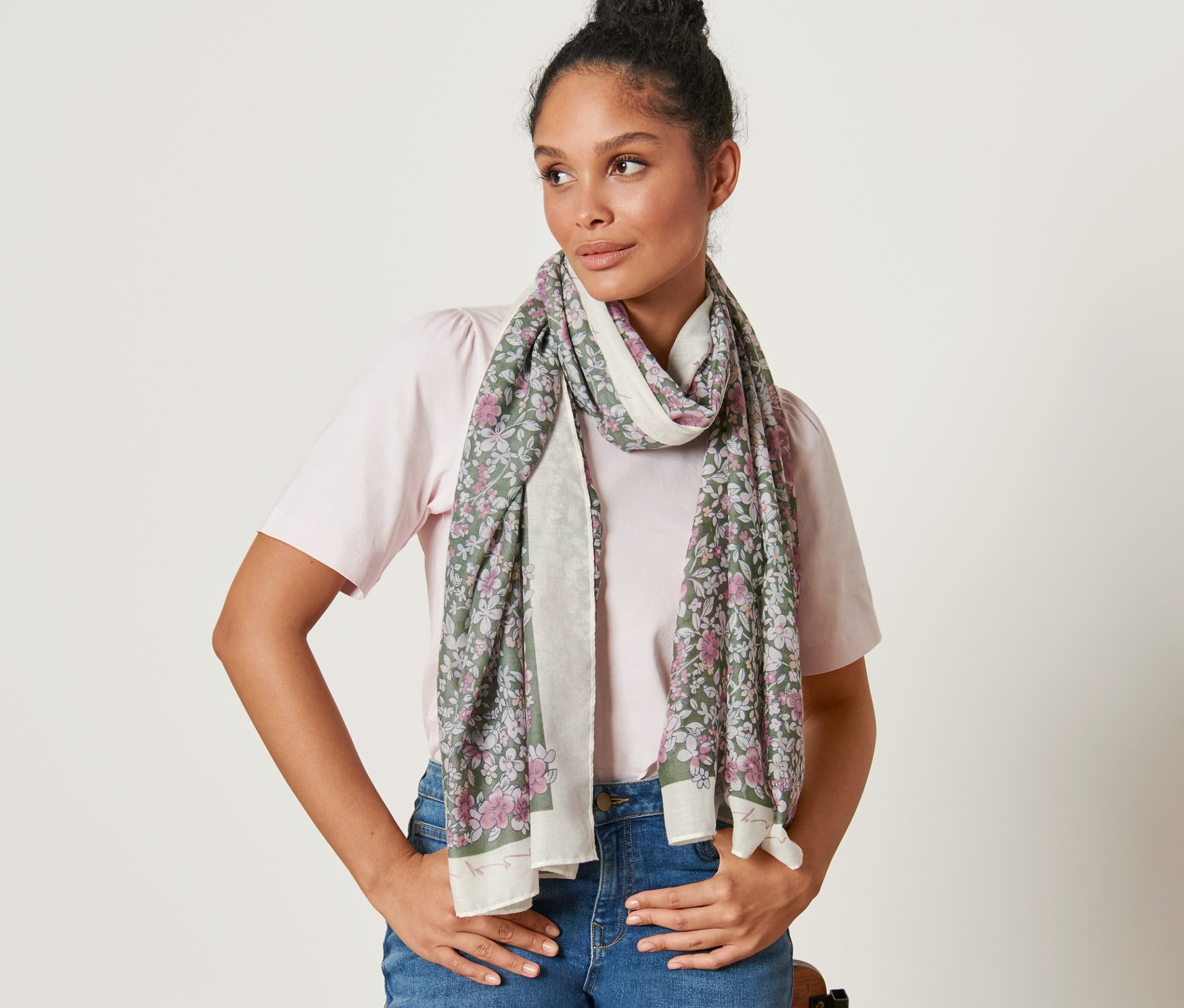 Kobieta z brązowymi włosami pozuje z tkanym szalem w kwiaty.