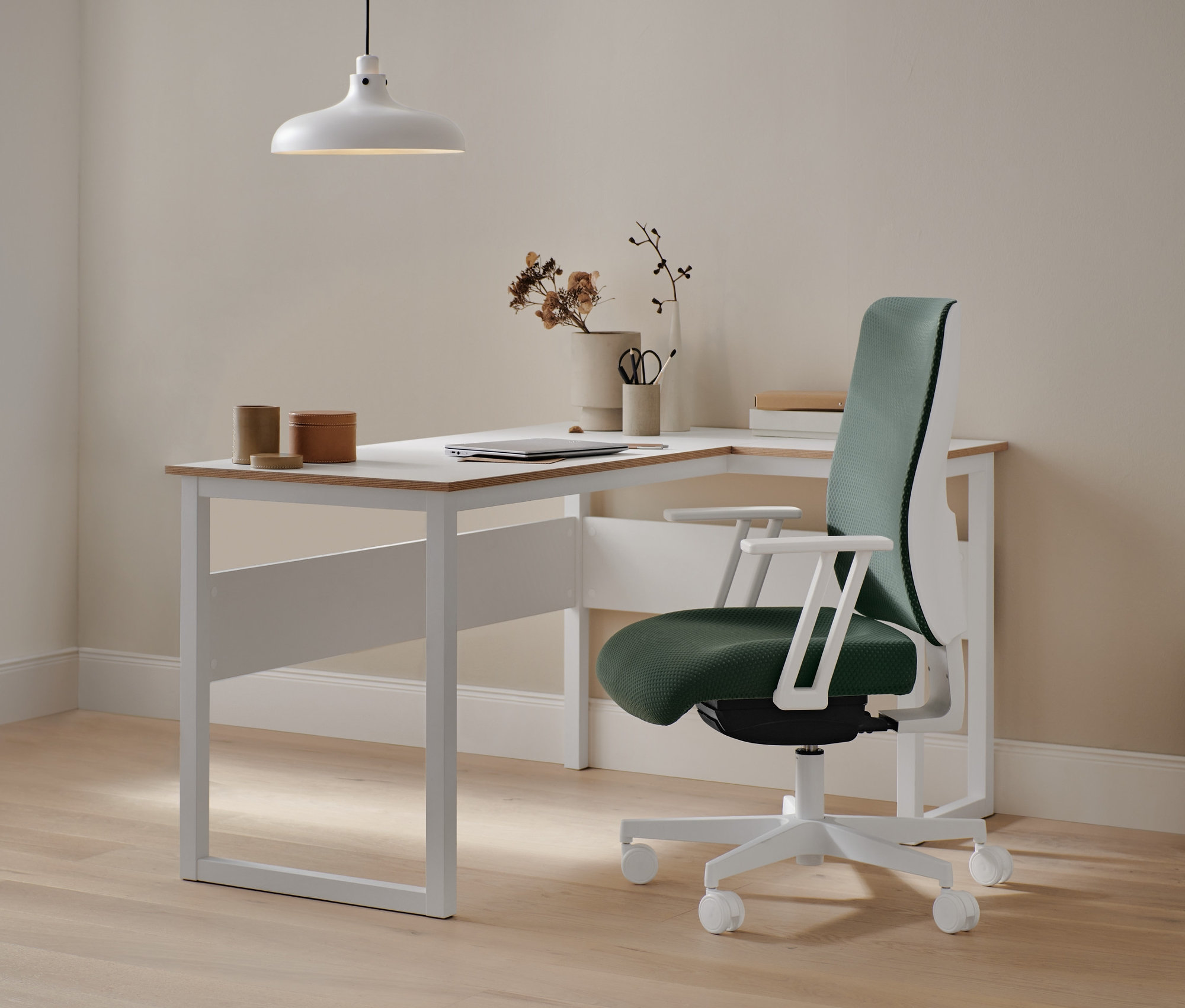 Biurko narożne z fornirowanymi krawędziami i metalowa lampa wisząca.