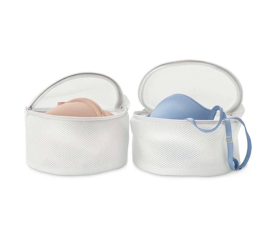 Dwa białe woreczki do prania biustonoszy, w każdym biustonosz.