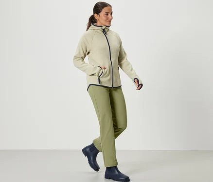 Kobieta idzie i ma na sobie spodnie softshellowe khaki.