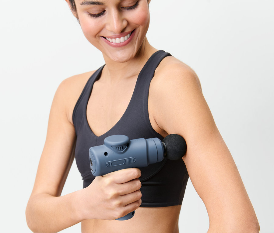 Kobieta używa minipistoletu do masażu na ramieniu.