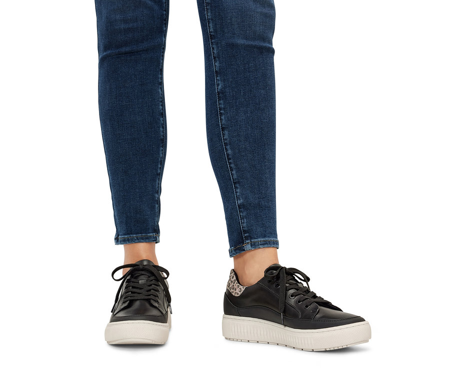 Nogi w jeansach i skórzane sneakersy.