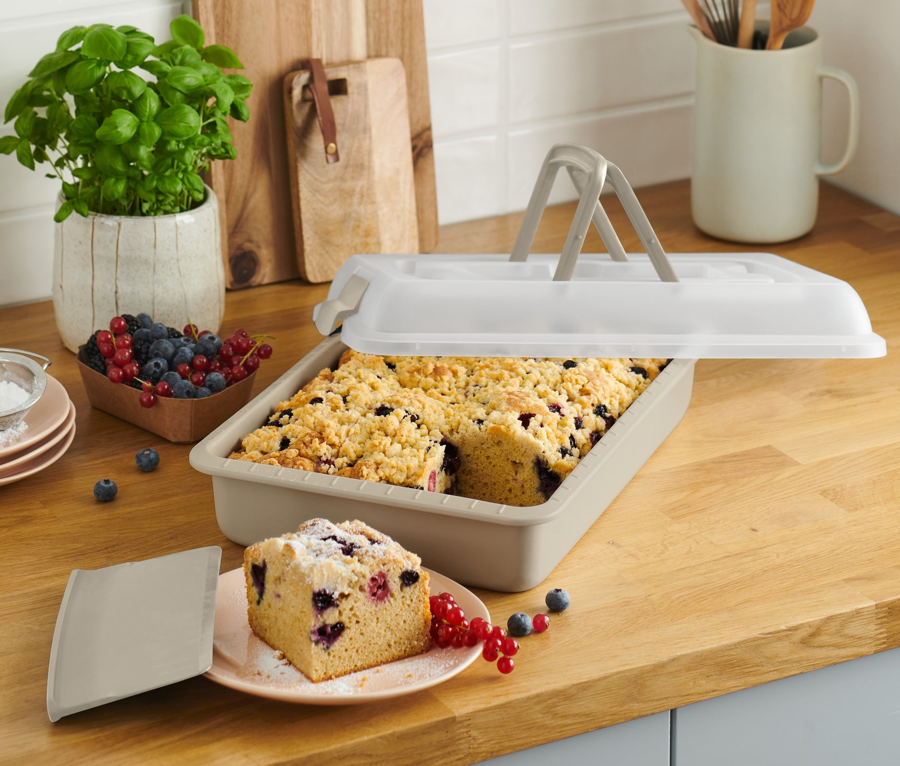 Blacha do pieczenia z pokrywką i kawałkiem ciasta na talerzu na blacie kuchennym.