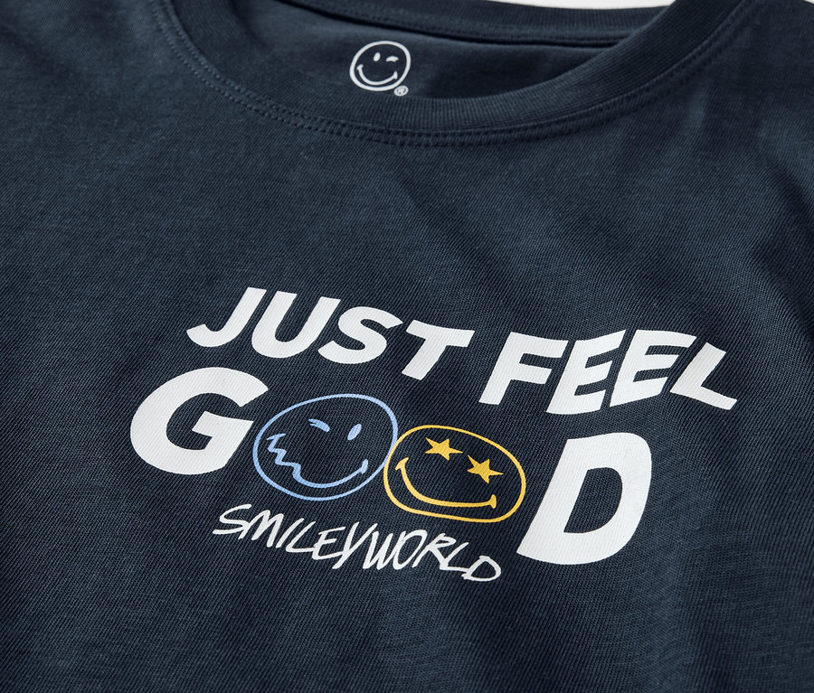 Zbliżenie na granatową koszulkę z napisem JUST FEEL GOOD i logo SMILEYWORLD. Piżama SMILEYWORLD®.
