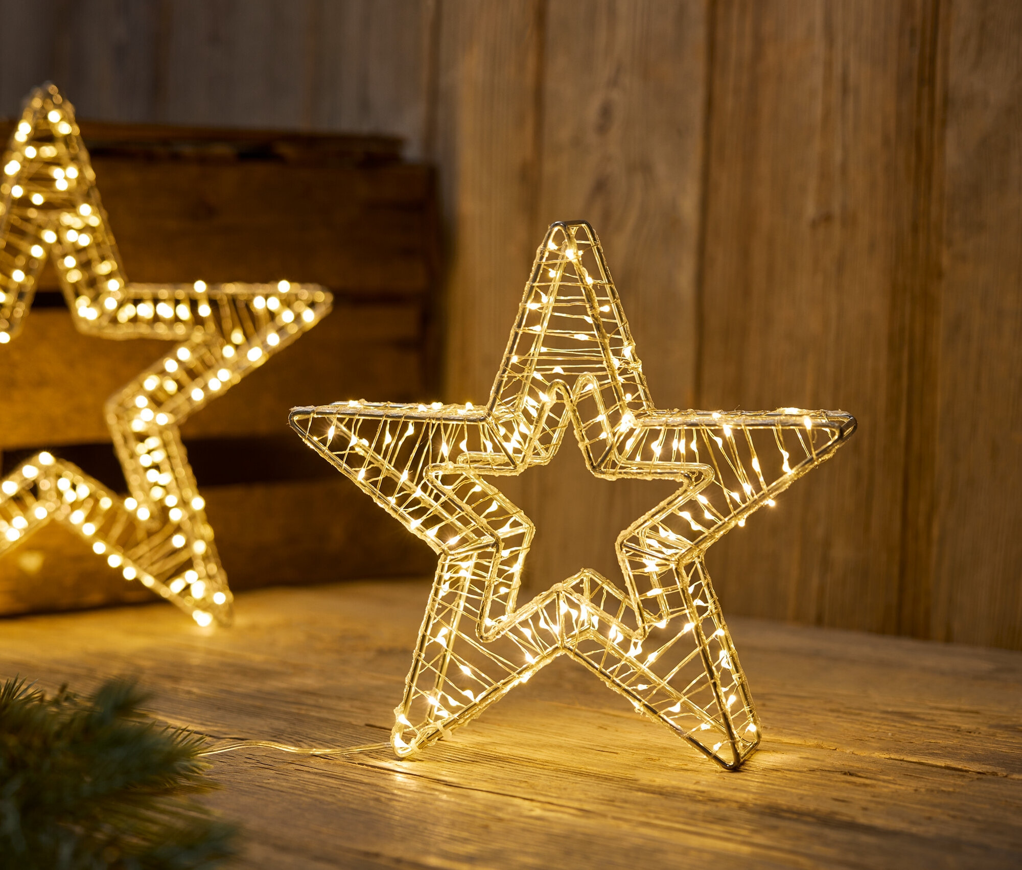 Oświetlone gwiazdy z drutu na drewnianej powierzchni.