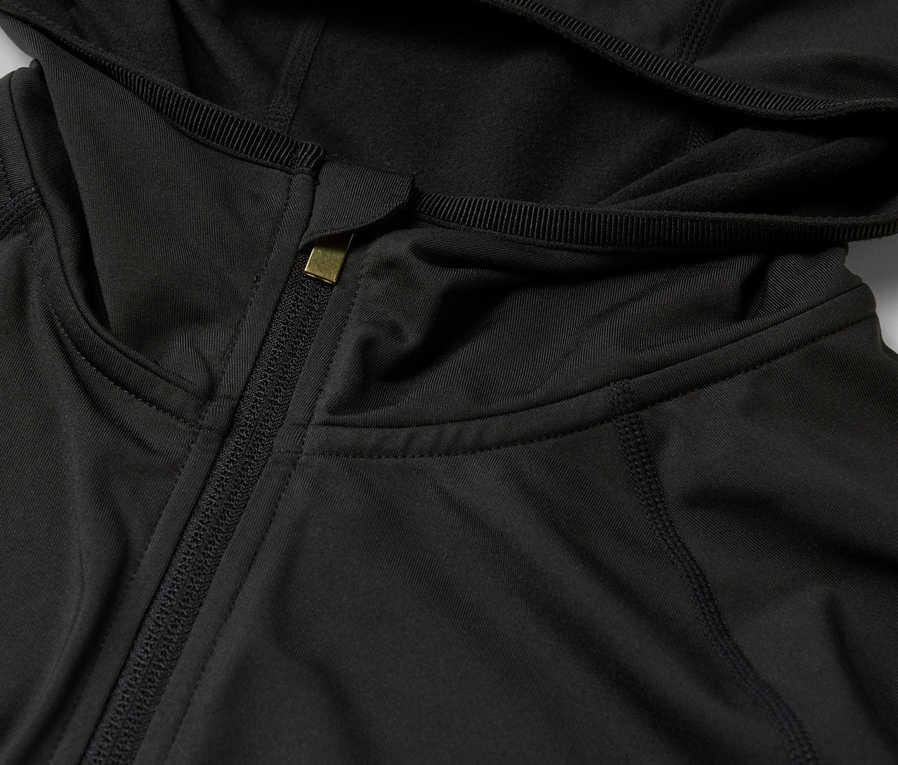 Zbliżenie na czarną bluzę z kapturem i zamkiem błyskawicznym.