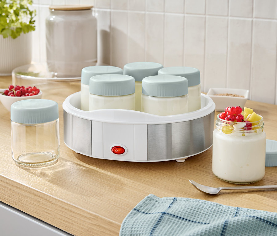 Jogurtownica z sześcioma szklankami i jedną szklanką jogurtu z owocami.