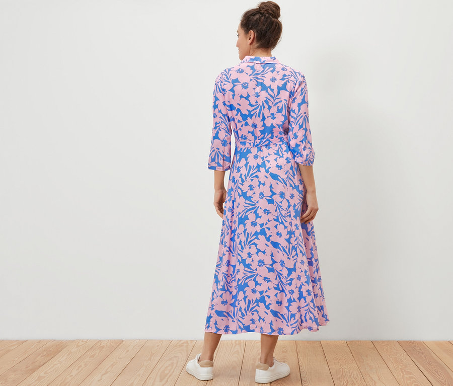 Kobieta tyłem do kamery ma na sobie wzorzystą sukienkę koszulową.