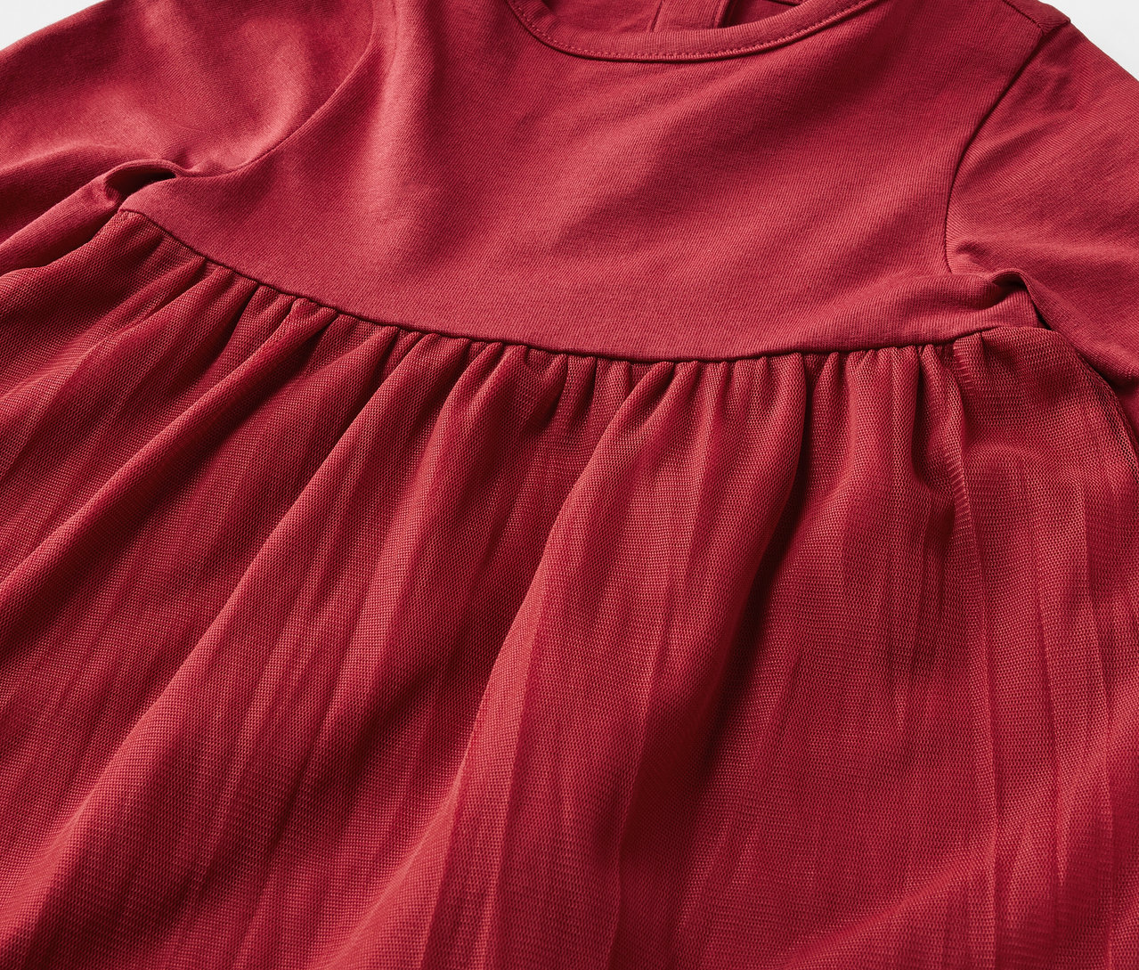 Zbliżenie na czerwoną sukienkę z długim rękawem i plisowaną spódnicą.