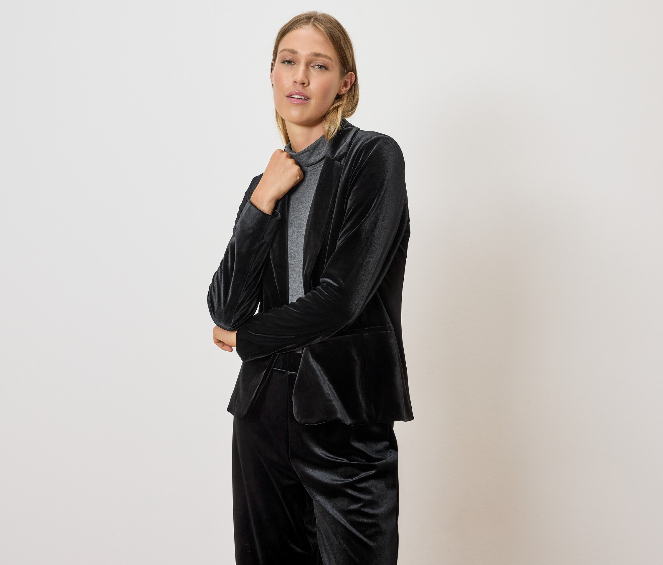 Kobieta pozuje w czarnej, welwetowej marynarce i spodniach.