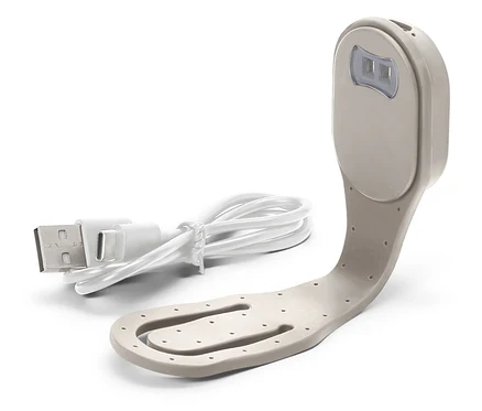 Zbliżenie beżowej lampki do czytania z białym kablem USB.