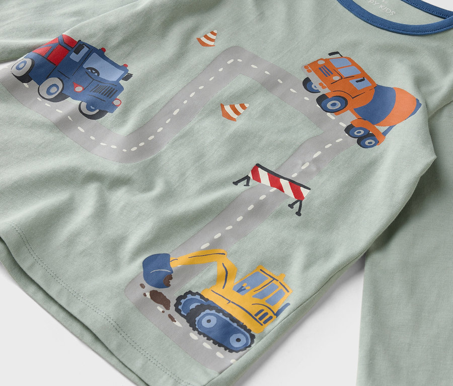Na jasnozielonej koszuli znajdują się ilustracje pojazdów budowlanych na szarej drodze.