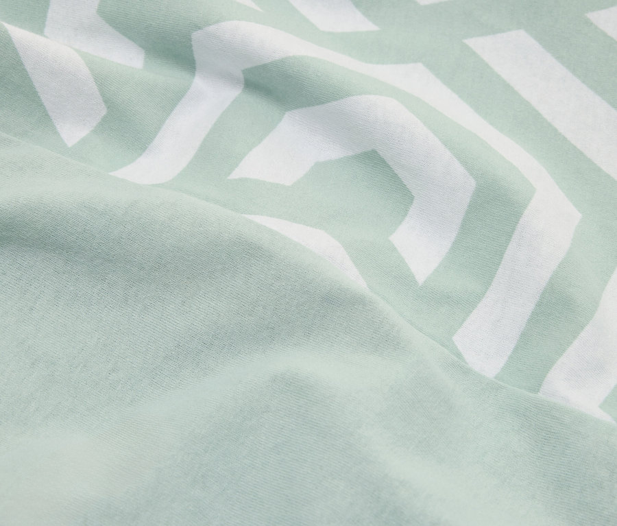 Zbliżenie miętowo-zielonej tkaniny z białym wzorem w zygzaki.