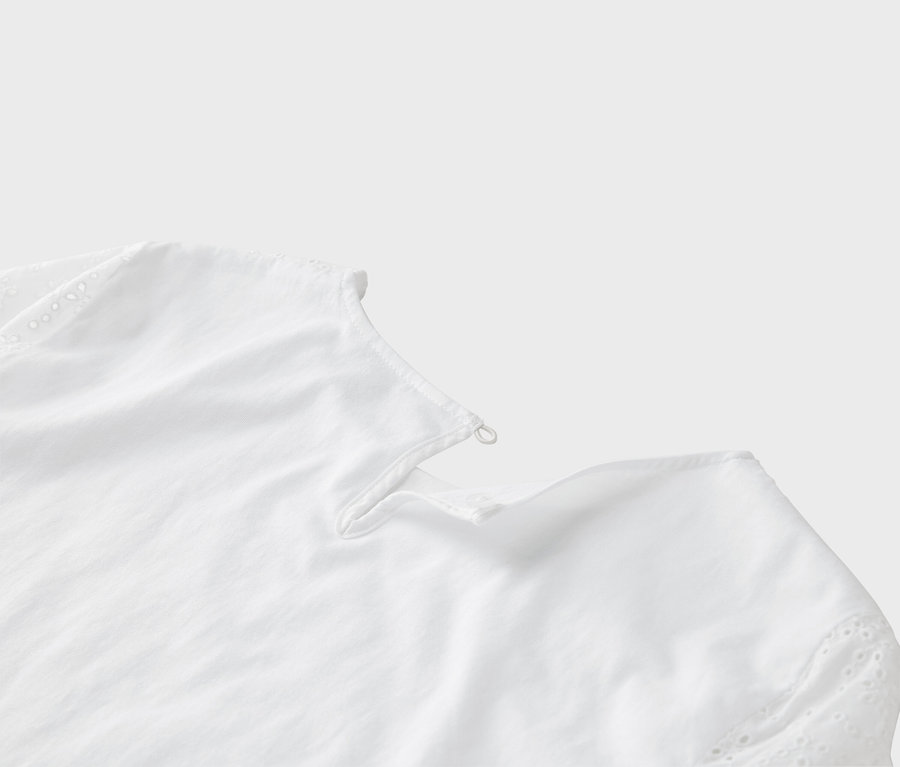 Szczegółowy widok białej bluzki z haftem dziurkowanym na rękawie.