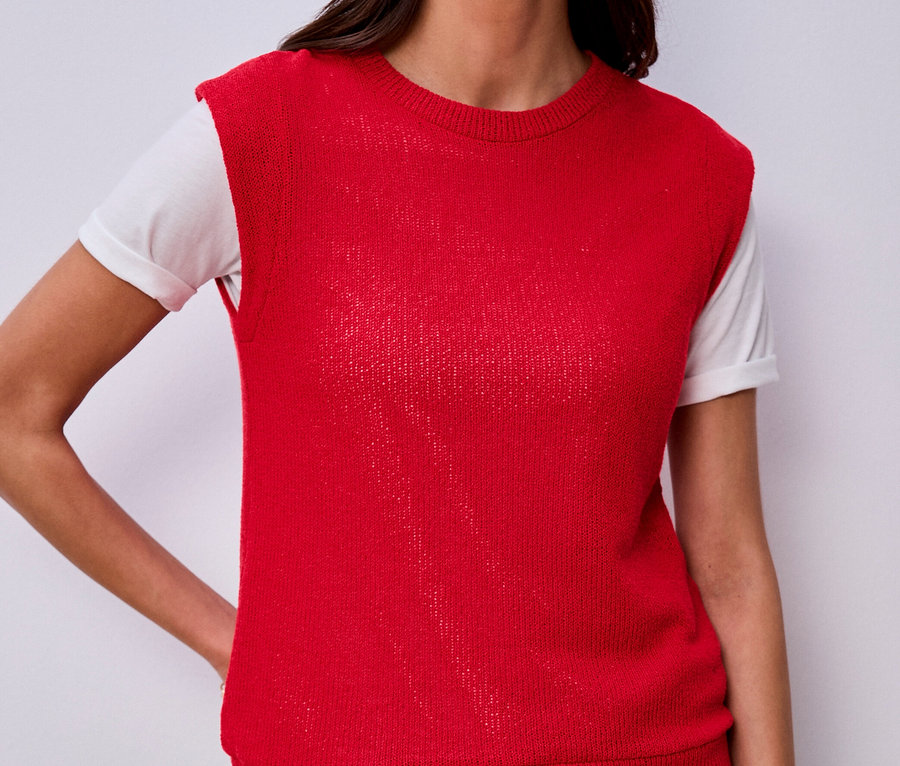 Kobieta w koszulce Street One pod czerwoną kamizelką i dżinsach, z ręką w kieszeni.