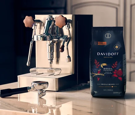Na marmurowej płycie stoi ekspres do kawy obok paczki kawy ziarnistej DAVIDOFF CAFÉ ORIGINS Brazil - 1x 1000 g.
