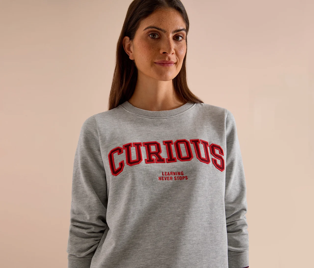 Kobieta w szarej bluzie CECIL z czerwonym napisem "CURIOUS" i "LEARNING NEVER STOPS".