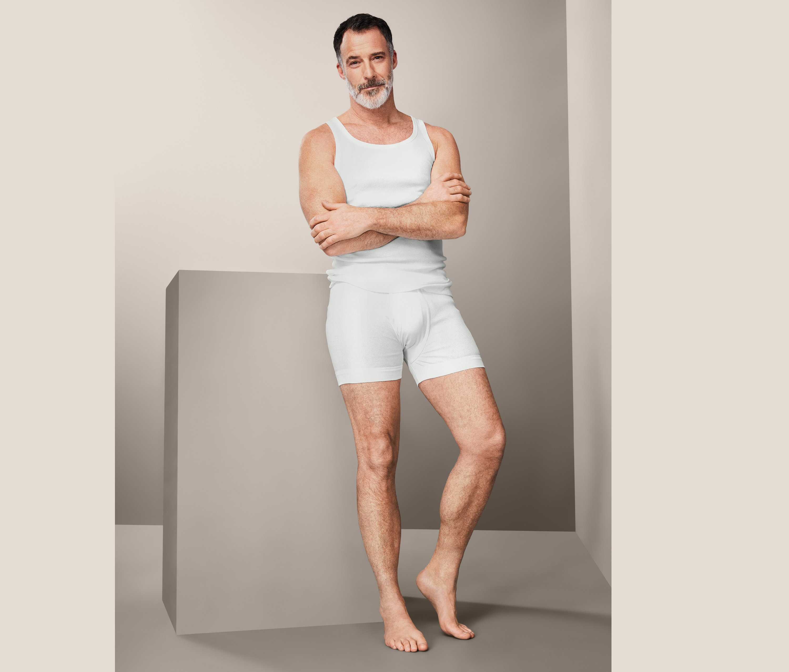 Mężczyzna pozuje w białym podkoszulku i bokserkach, 2 pary.
