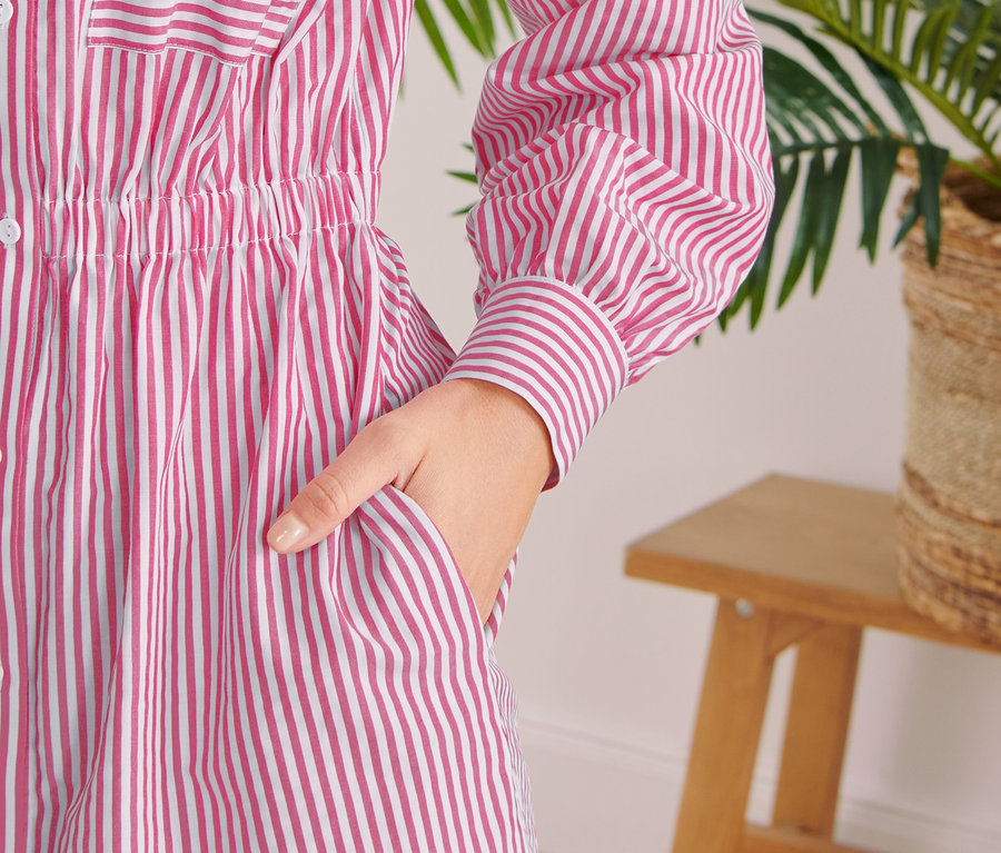 Zbliżenie na sukienkę koszulową w paski z ręką w kieszeni.
