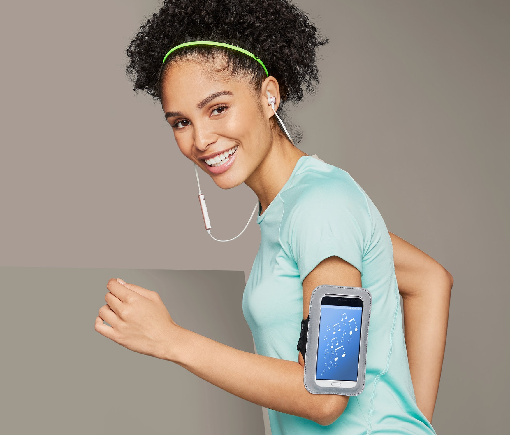 Kobieta biegnie z sportową opaską na ramię na smartfon.