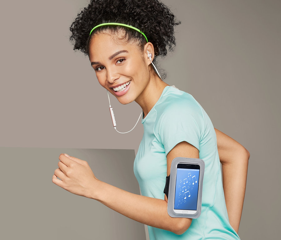 Kobieta biegnie z sportową opaską na ramię na smartfon.