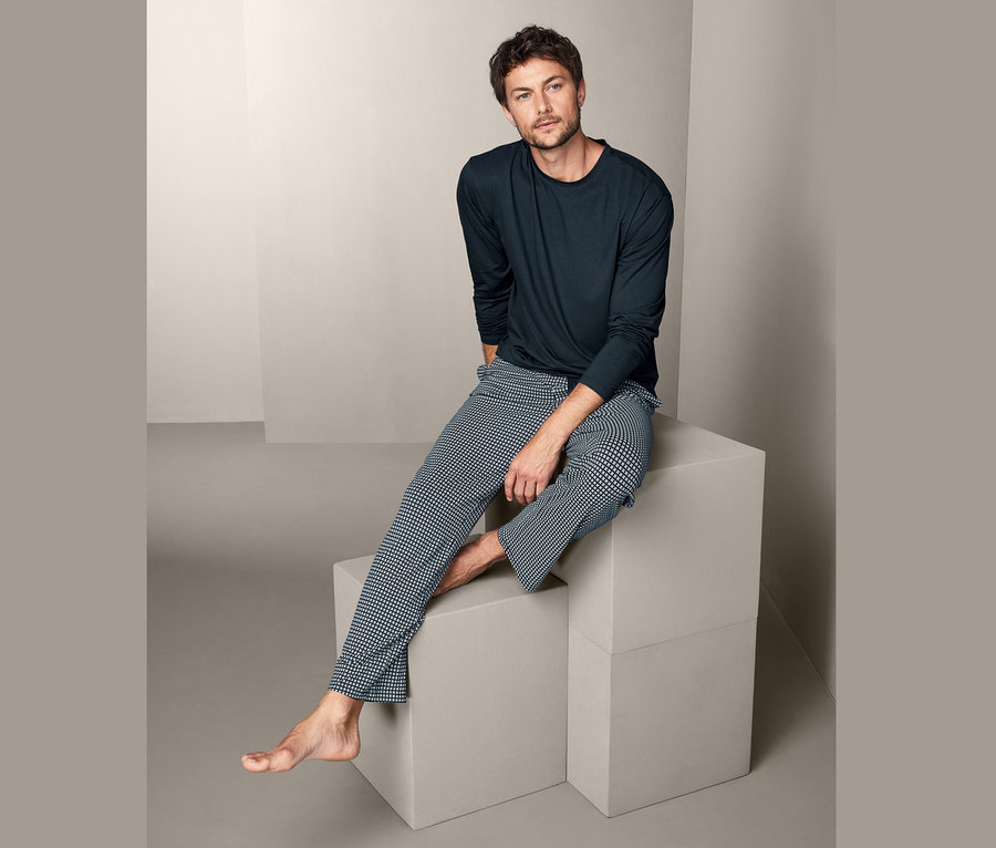 Mężczyzna siedzi na kostkach w piżamie męskiej.