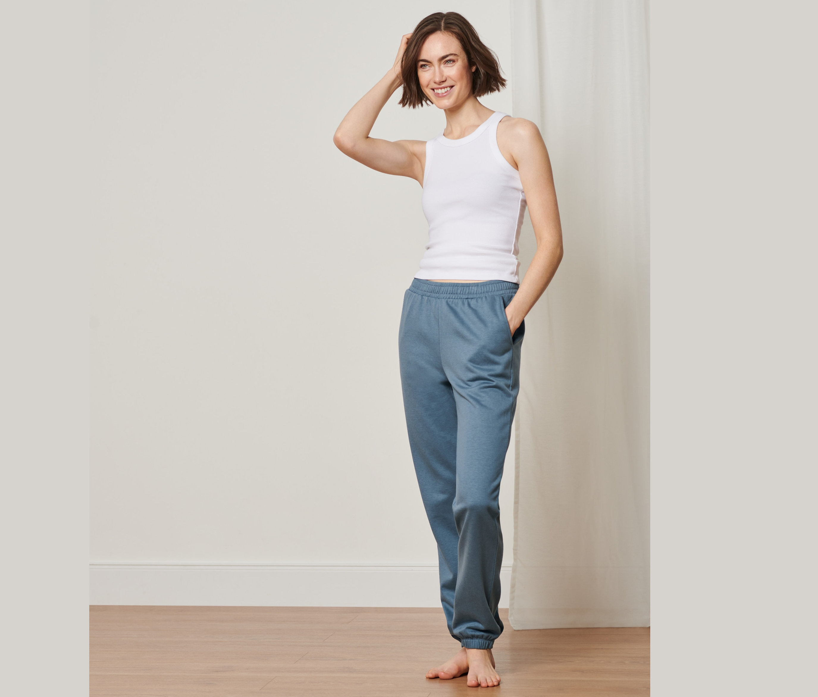 Kobieta pozuje w podkoszulku i spodniach rekreacyjnych.