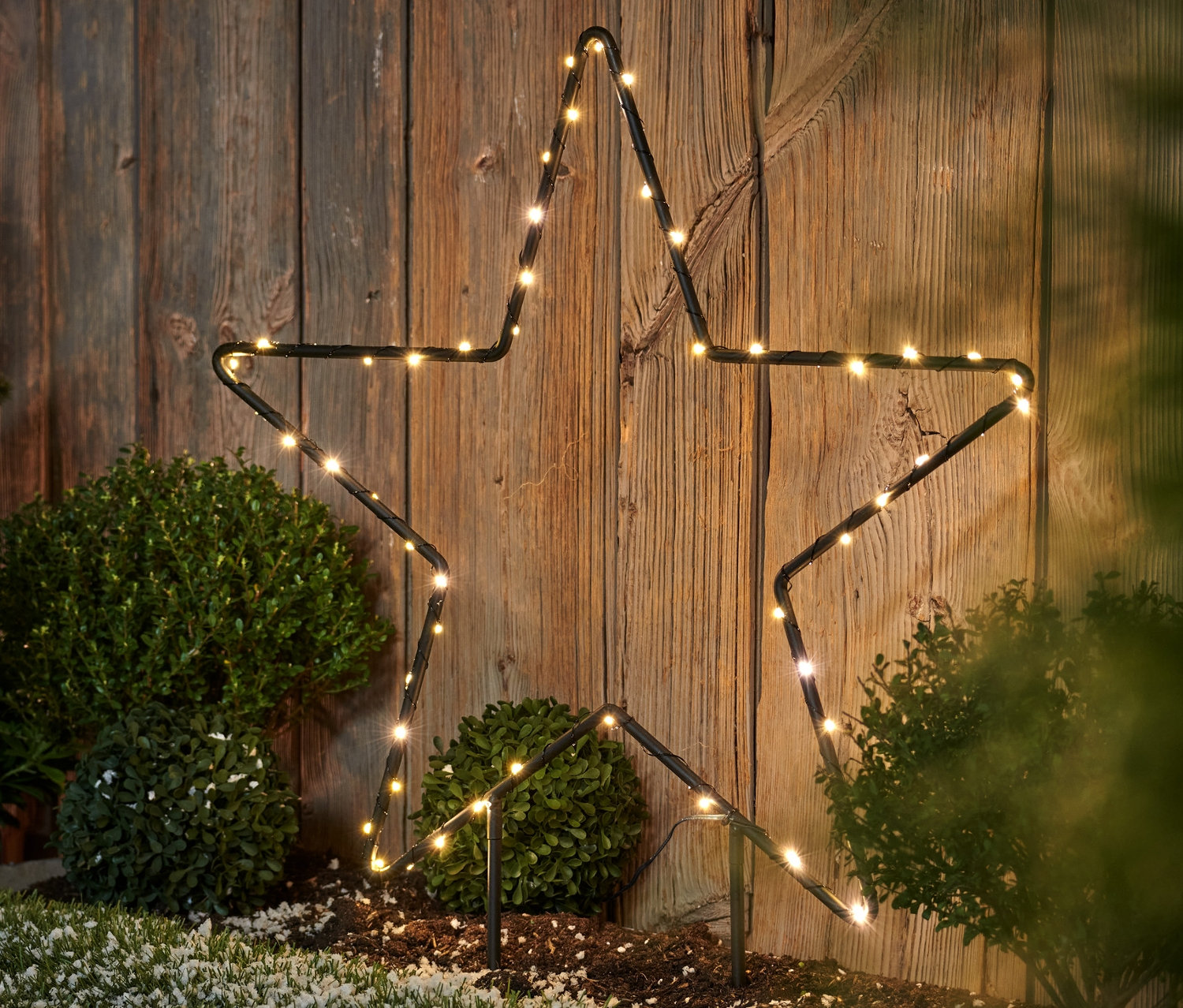 Metalowa gwiazda LED do użytku na zewnątrz, duża, stoi na trawniku.