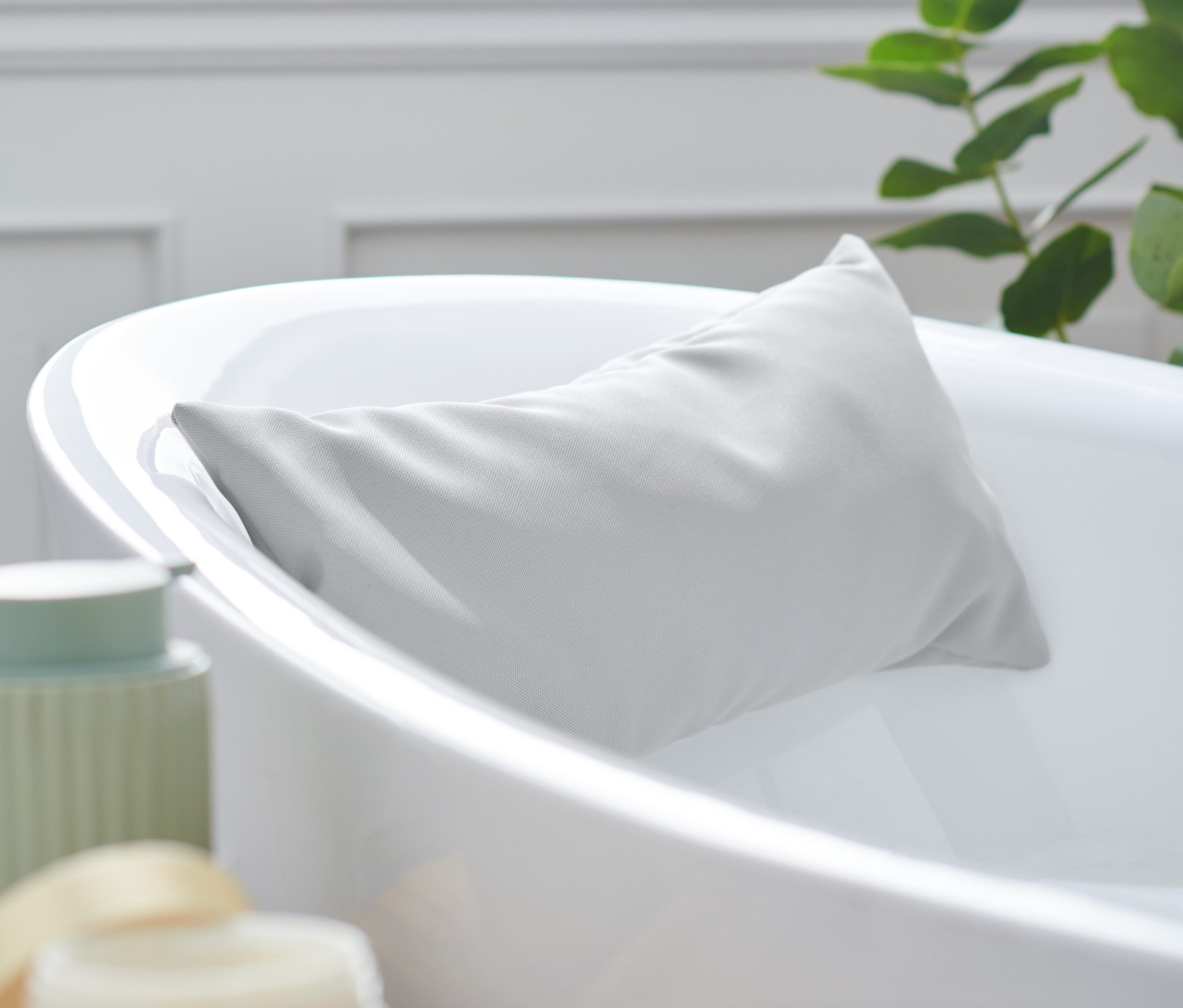 Szara poduszka do wanny opiera się o brzeg białej wanny.