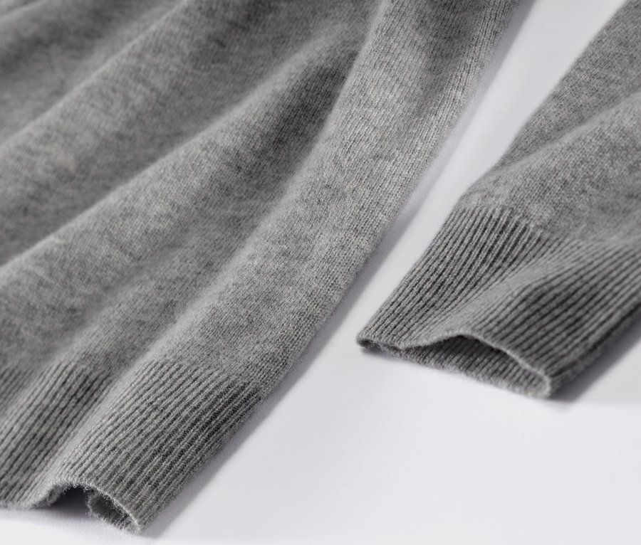 Zbliżenie na szary melanżowy sweter z delikatnej dzianiny z kaszmirem.