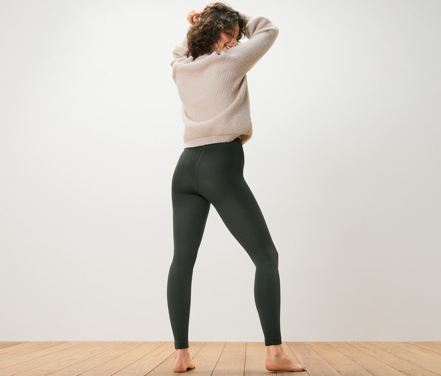 Kobieta stoi tyłem do aparatu, ubrana w prążkowane legginsy termoaktywne.