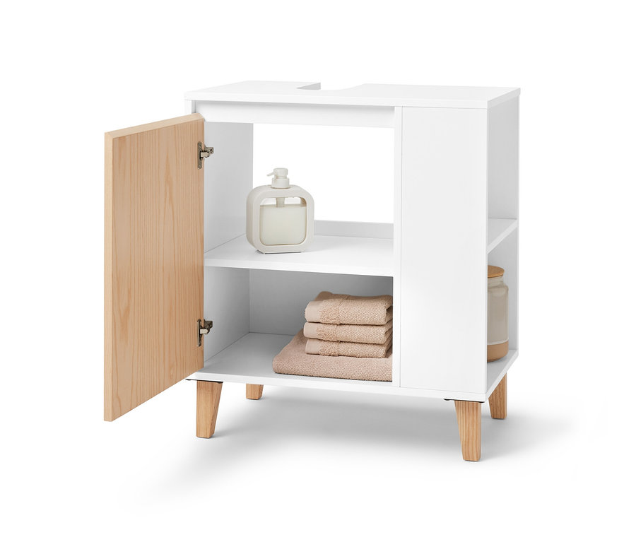 Otwarta, biała szafka pod umywalkę z boczną przegródką. Na półkach leżą ręczniki i dozownik mydła.